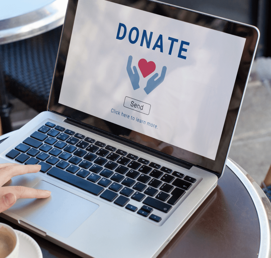 Person donating online using a laptop with a donate sign on screen.